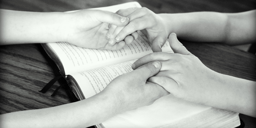 Über einem Buch reichen sich zwei Menschen ihre Hände.